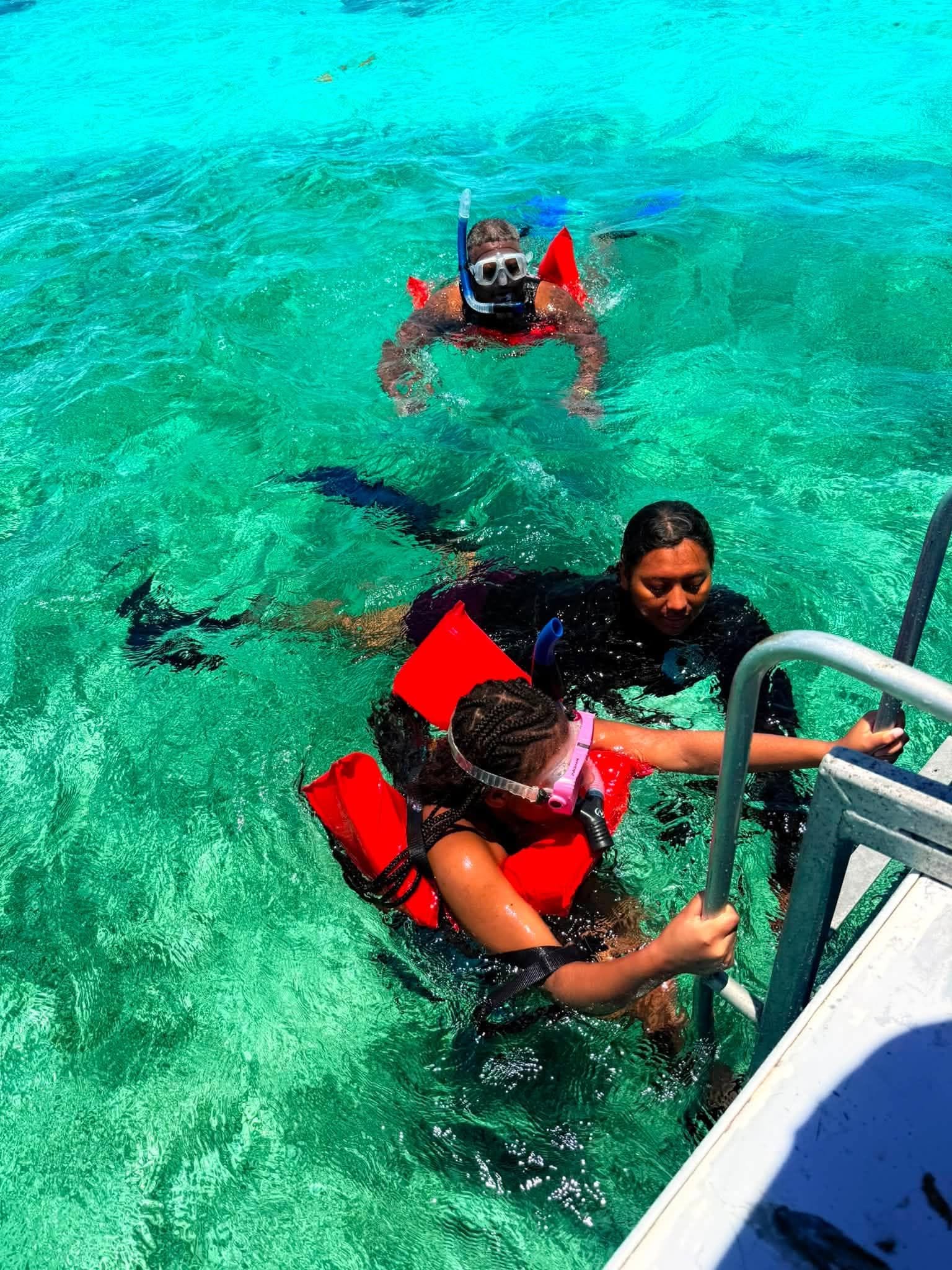 Snorkelers wearing masks and flotation vests beside the boat